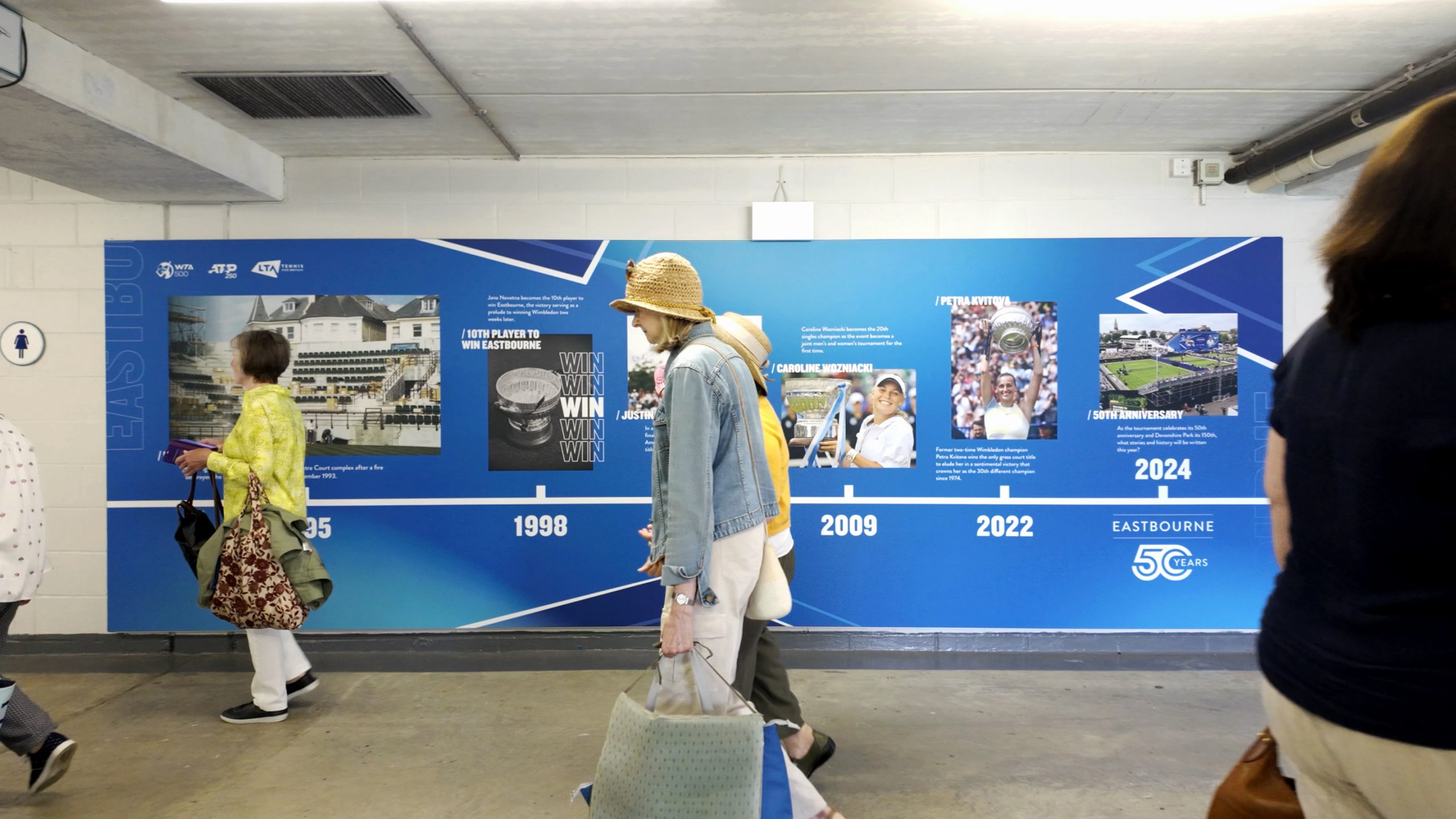 Spectators walking through the Eastbourne Tennis players’ tunnel featuring timeline wall graphics produced and installed by Beautiful LFP at Devonshire Park.