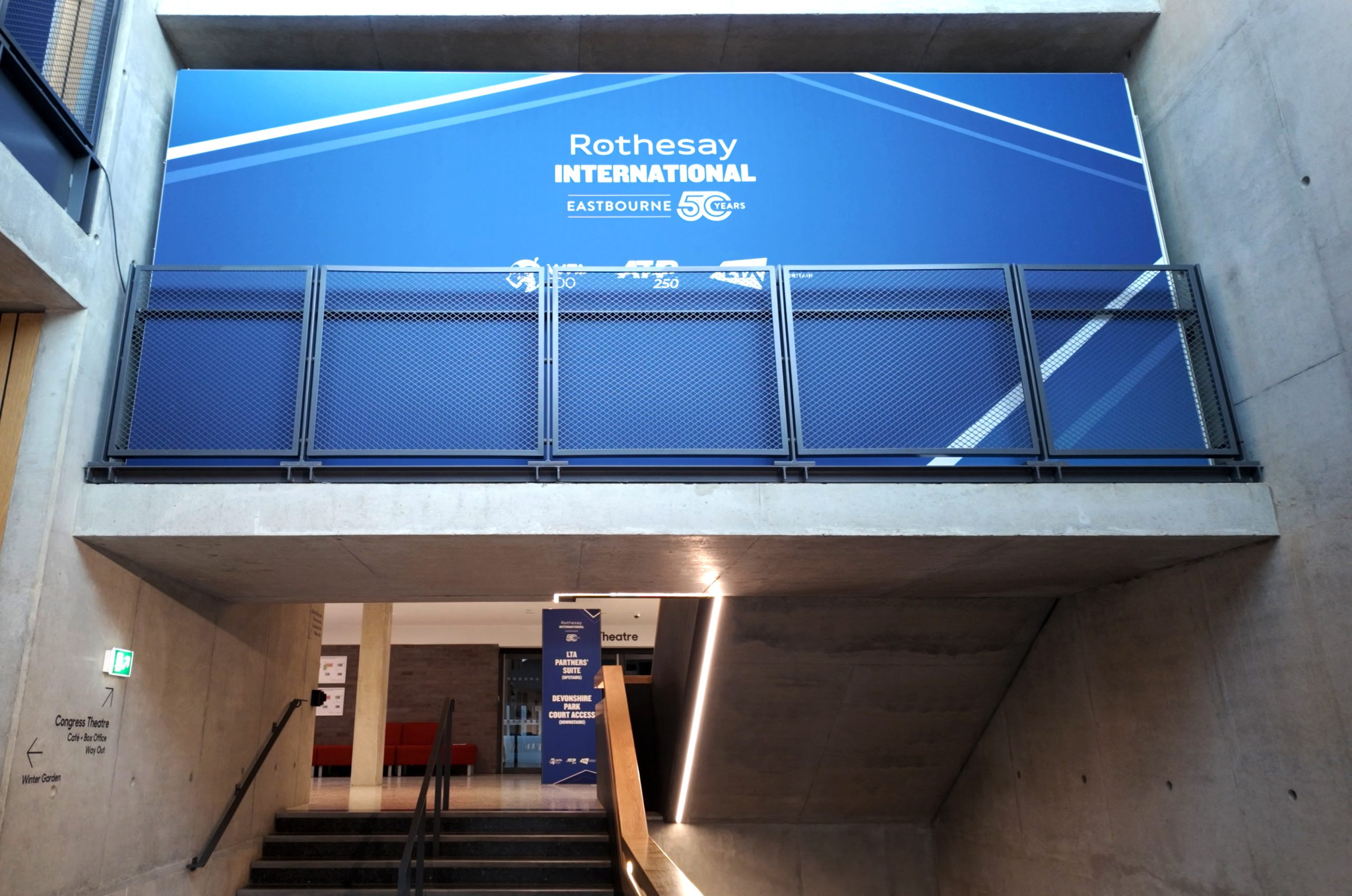 Branded staircase installation at Devonshire Park Tennis Centre featuring Rothesay International Eastbourne signage produced by Beautiful LFP.