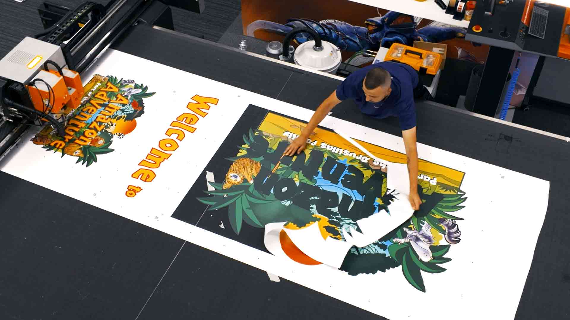 Large-format printer producing vibrant “Amazon Adventure” graphics for Drusillas Park signage.