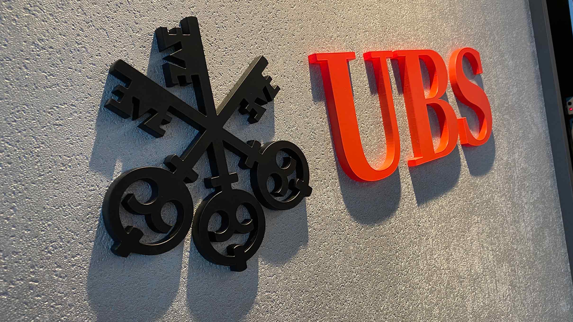 Close-up of UBS 3D wall logo featuring black key emblem and red lettering inside the VIP Lounge at Chelsea FC, produced by Beautiful LFP.